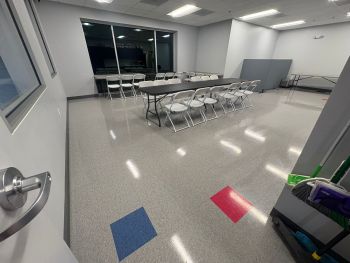 Clean business break room with folding chairs, tables, and a janitorial cart